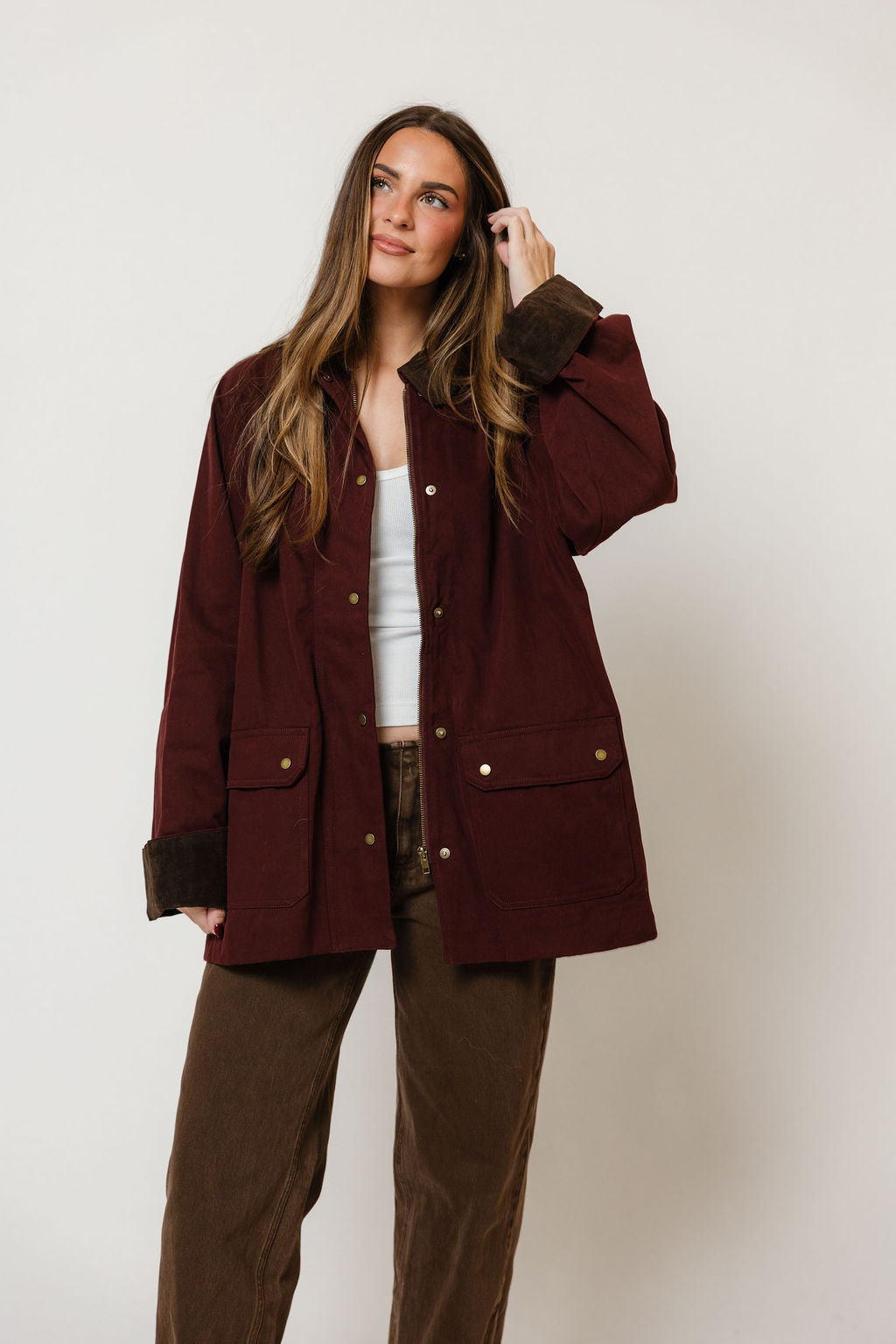 Model in the Montana barn coat in deep maroon with a collar and front pockets, worn over a white top and brown pants