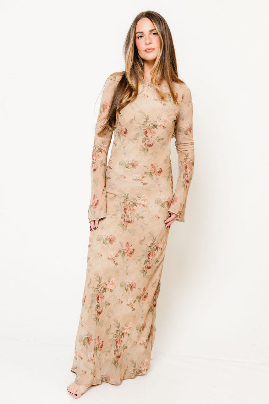 Model in the Georgie long sleeve fitted maxi dress in tan with a soft floral print and a crew neck