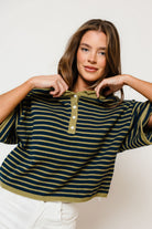 Model in the Jagger striped knit sweater in navy with thin matcha green stripes, a collared half-button neck, dropped shoulders and short sleeves