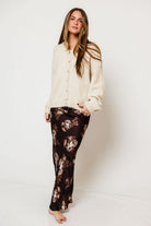Model in the Kirana satin maxi skirt in dark brown with a peach floral print, worn with a cream knit sweater
