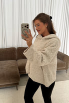 Mirror selfie of a model in the Tilly oversized chunky knit hooded sweater in cream oatmeal, worn with black pants